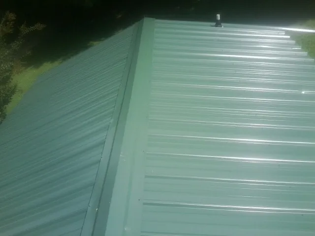 New green metal panels meeting at the ridge of a roof — Flat Roof Repair work by our crew in Vintondale