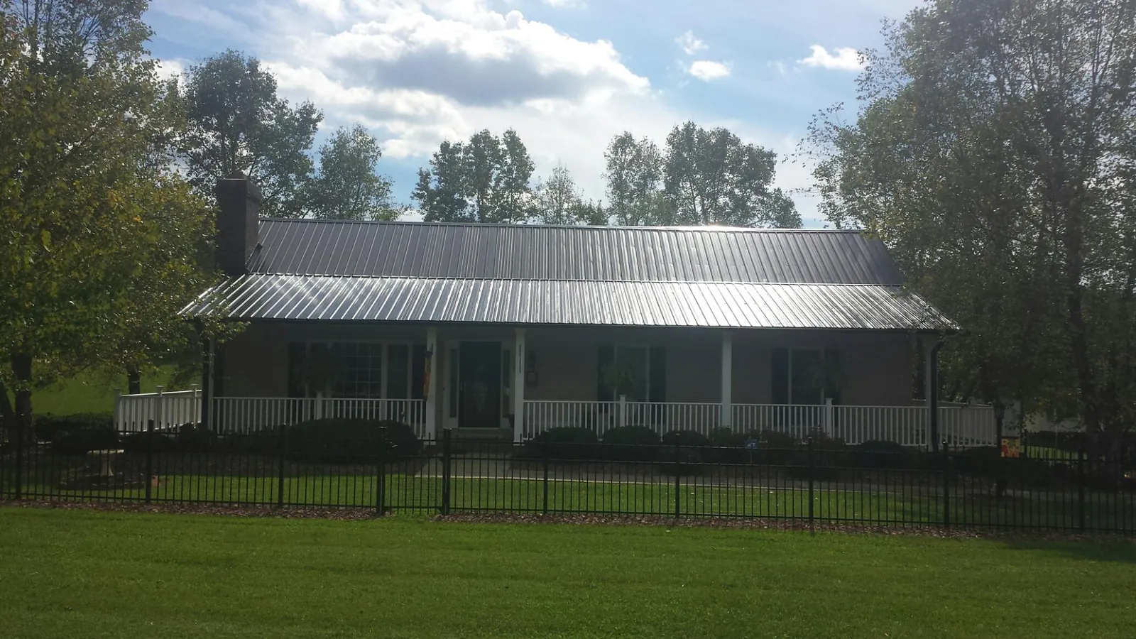 Gray metal roof on a brick ranch with a full width front porch — Gutter Guard Installation work by our crew in Vintondale