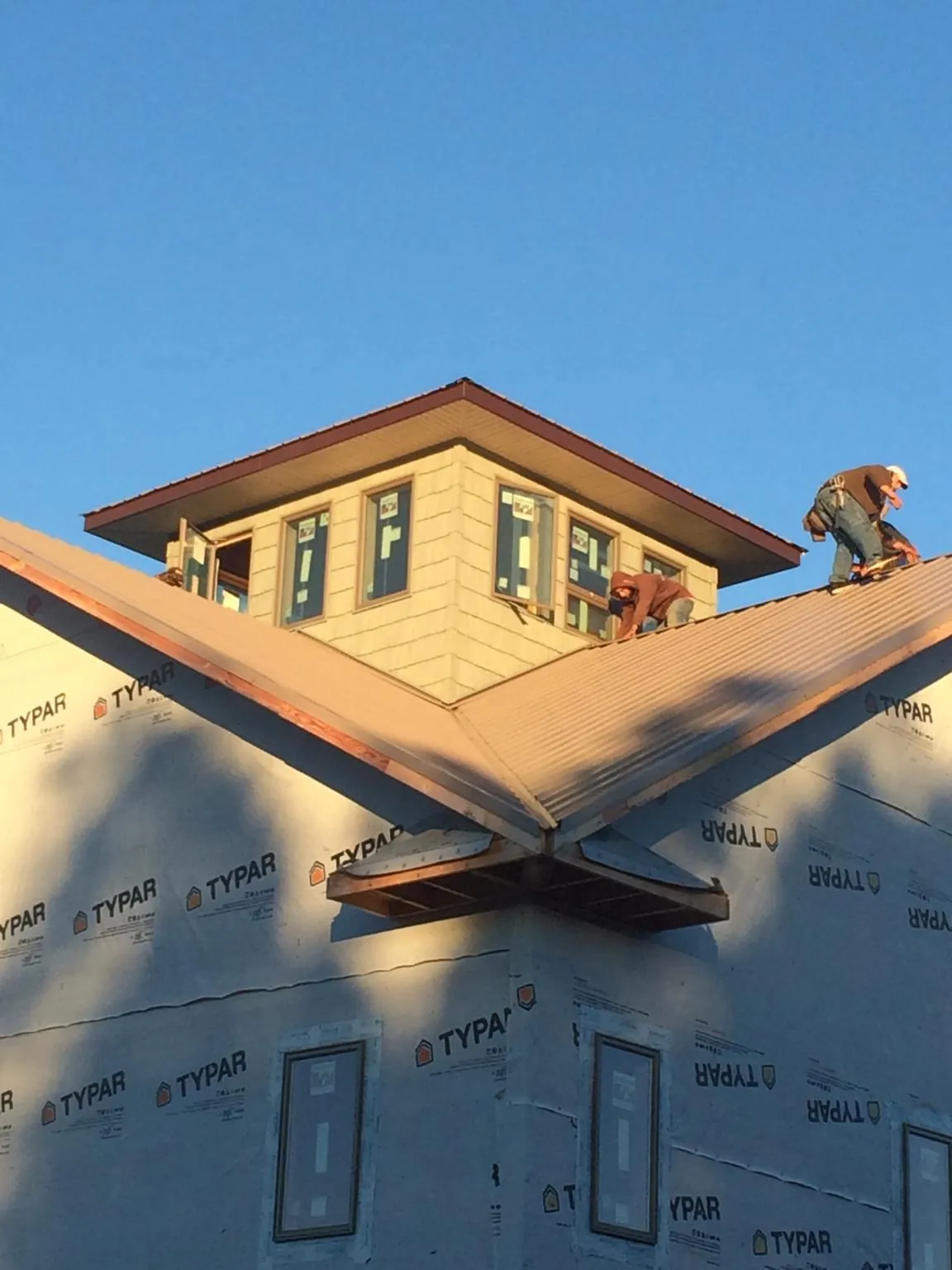 Roofers working around a rooftop cupola on a new metal roof at sunset — Roof Waterproofing in Vintondale by Roofing Brothers